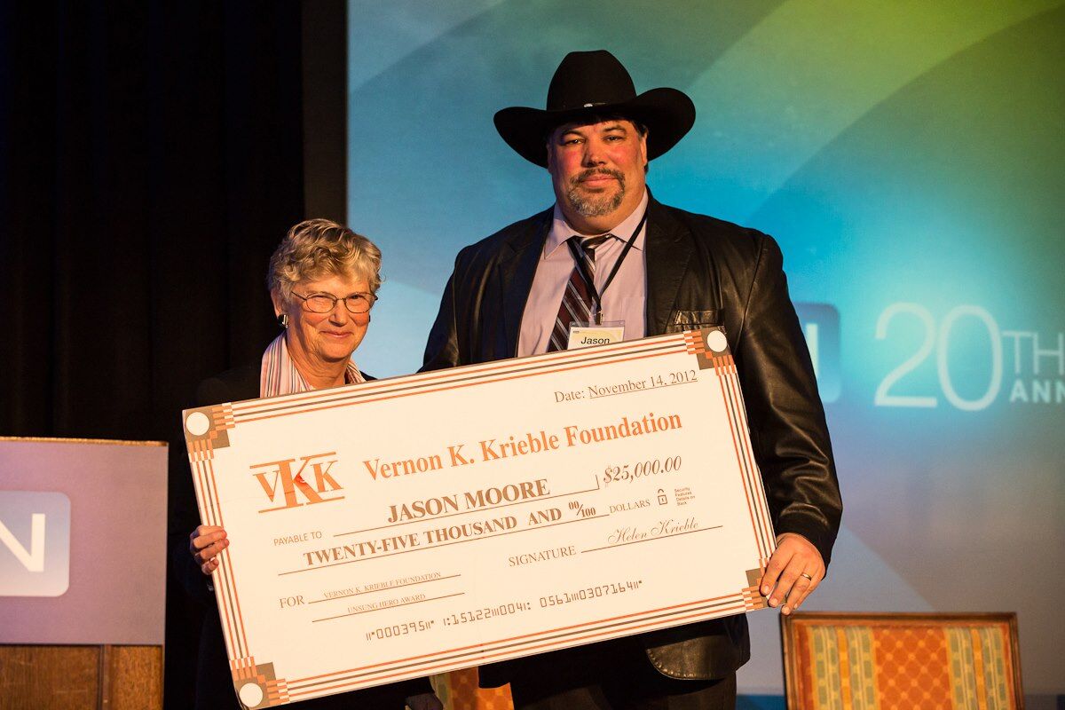 Jason Moore accepting a large check from Helen Krieble